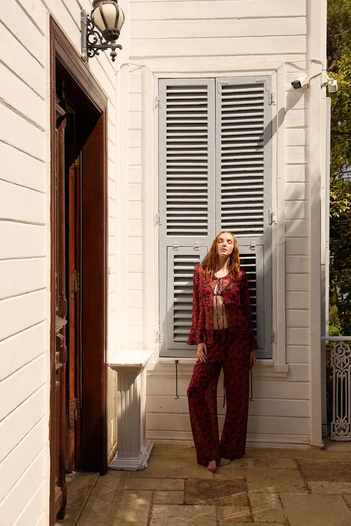 Woman standing in front of a white house with gray shutters.
