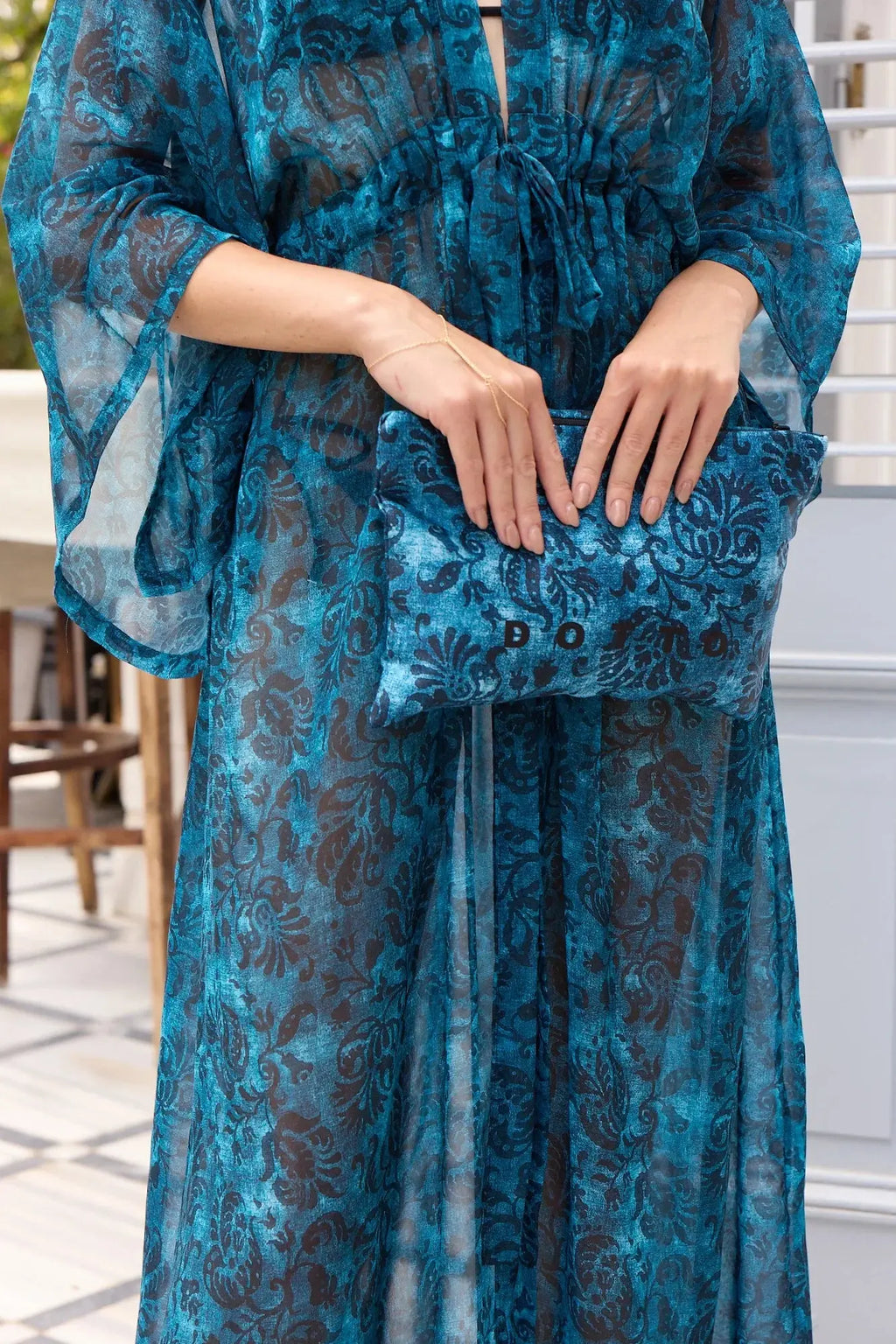 Woman wearing a blue floral dress with a matching handbag outdoors.