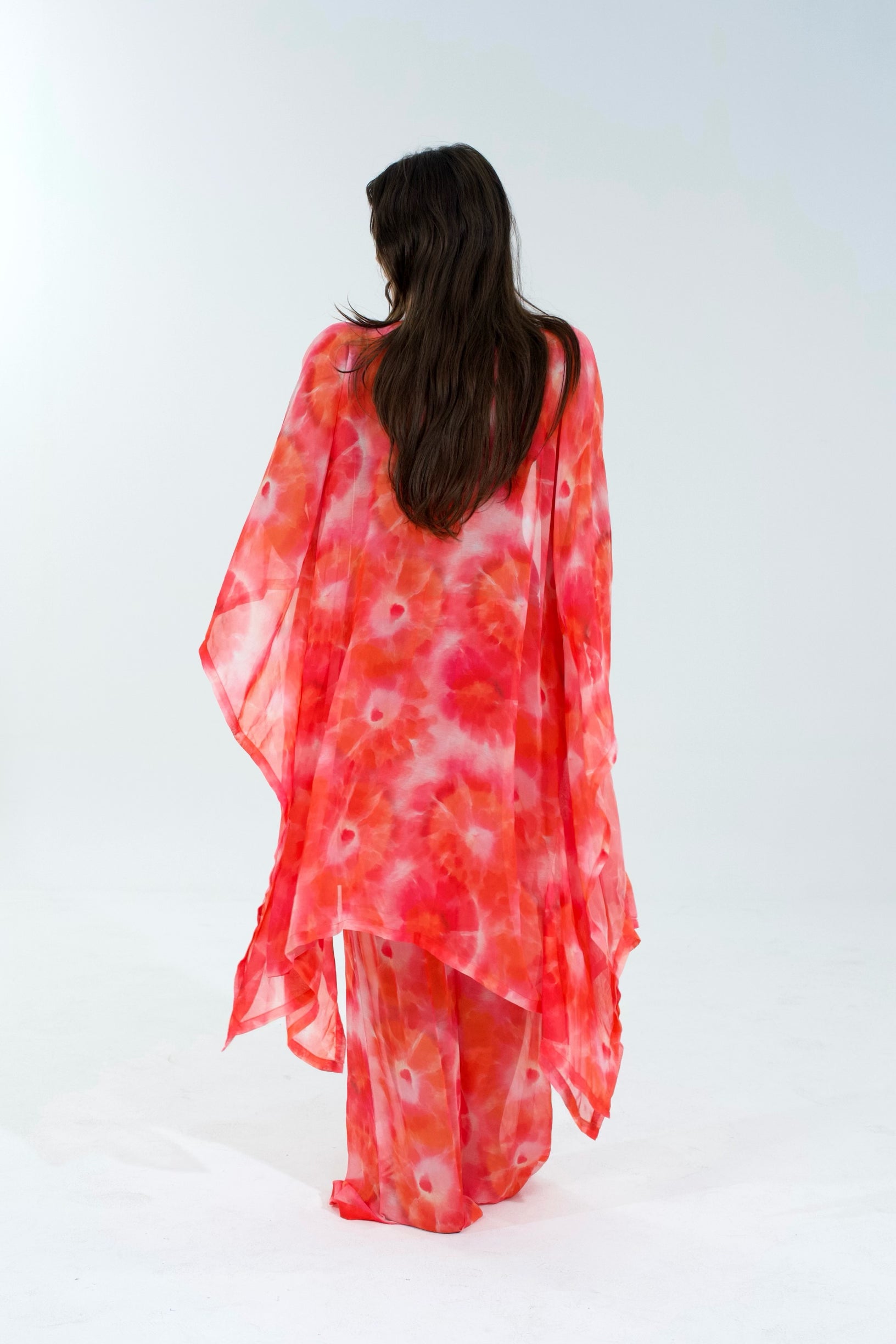 Woman wearing a red and white tie-dye kimono-style garment on a white background