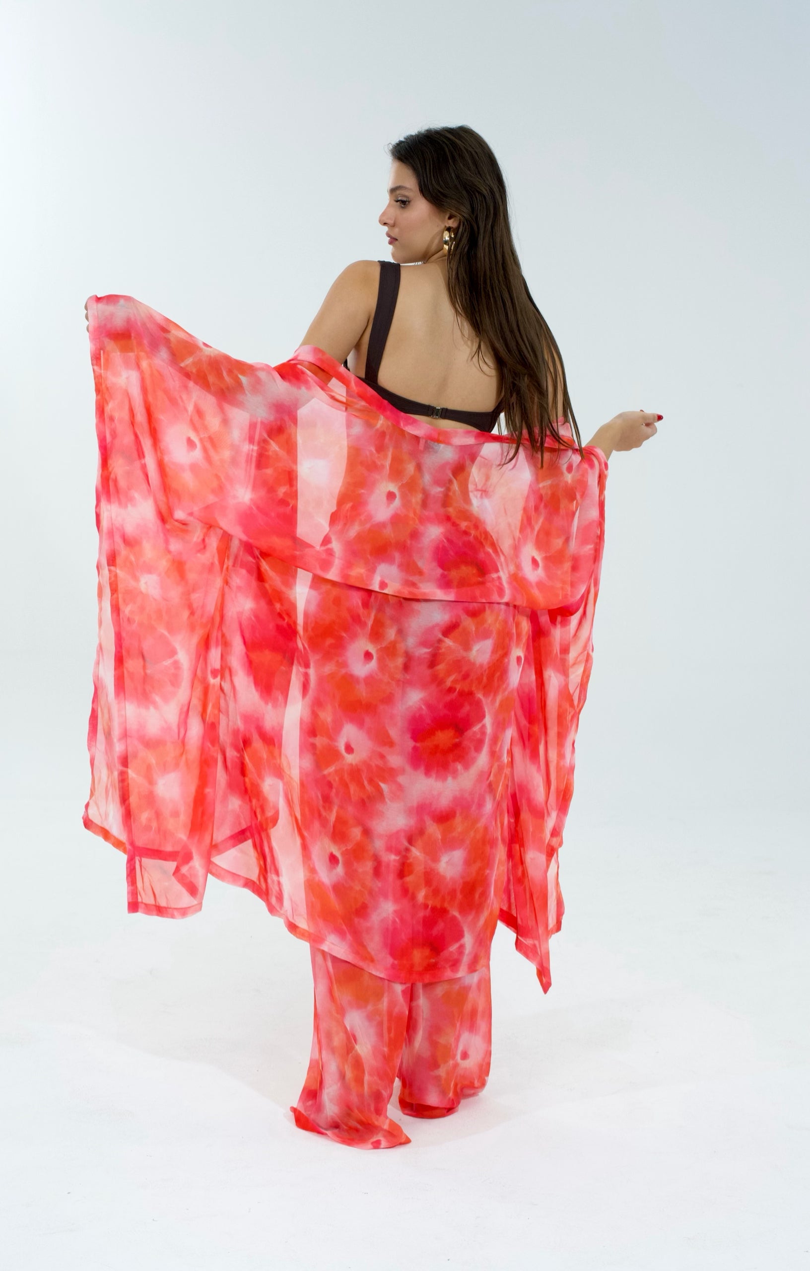 Woman wearing a red and white tie-dye cover-up on a white background