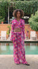Woman in a colorful outfit standing by a pool with greenery in the background